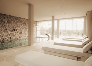 Ein modernes Interieur mit einer Steinwand, großen Fenstern und einem Poolbereich.