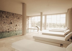 Ein modernes Interieur mit einer Steinwand, großen Fenstern und einem Poolbereich.