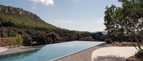 A swimming pool with a clear view of the surrounding landscape, including trees and hills.