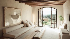 A room with a large window, a sofa, a bench, and a painting on the wall. - Es Racó D Artá (Arta)