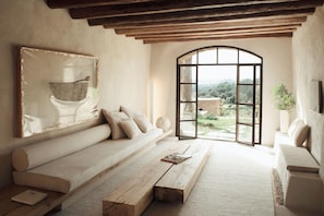 Ein Zimmer mit einem großen Fenster, einem Sofa, einer Bank und einem Gemälde an der Wand.