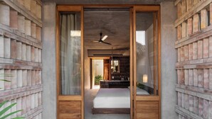 A room with a bed, a ceiling fan, and a view through a wooden door. - Hotel Humano (Santa María Colotepec)