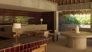 A modern interior with a thatched roof, a tiled bar area, and a view of greenery outside. - Hotel Humano (Santa María Colotepec)