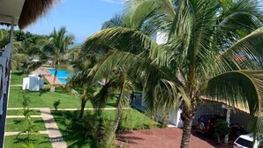 A view of a resort with palm trees, a pool, and a red-roofed building. - Mar De Estrellas (Papantla de Olarte)