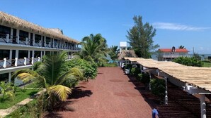 A resort with a thatched-roof building, a paved walkway, and palm trees. - Mar De Estrellas (Papantla de Olarte)