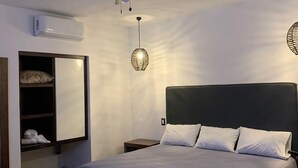 A modern bedroom with a large bed, a ceiling fan, a wall-mounted air conditioner, and a bedside table with a lamp. - Mar De Estrellas (Papantla de Olarte)
