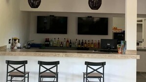 A modern kitchen with a bar area, two hanging wicker light fixtures, a ceiling fan, and a row of bottles on the counter. - Mar De Estrellas (Papantla de Olarte)