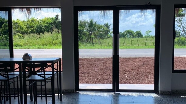 A room with a large sliding glass door leading to a road, a tiled floor, and a table with chairs. - Mar De Estrellas (Papantla de Olarte)
