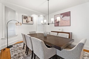 A dining room with a rectangular table, six chairs, a chandelier, and two wall-mounted lamps. - Expansive 4BD - Steps from downtown - Oak Park (Oak Park)