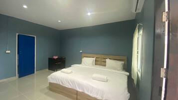 A bedroom with a bed, a blue door, a nightstand, and an air conditioning unit.