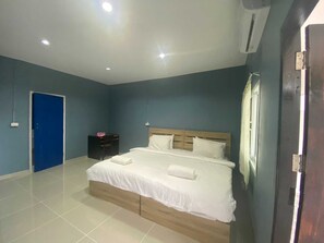 Un dormitorio con cama, una puerta azul, una mesita de noche y un equipo de aire acondicionado.