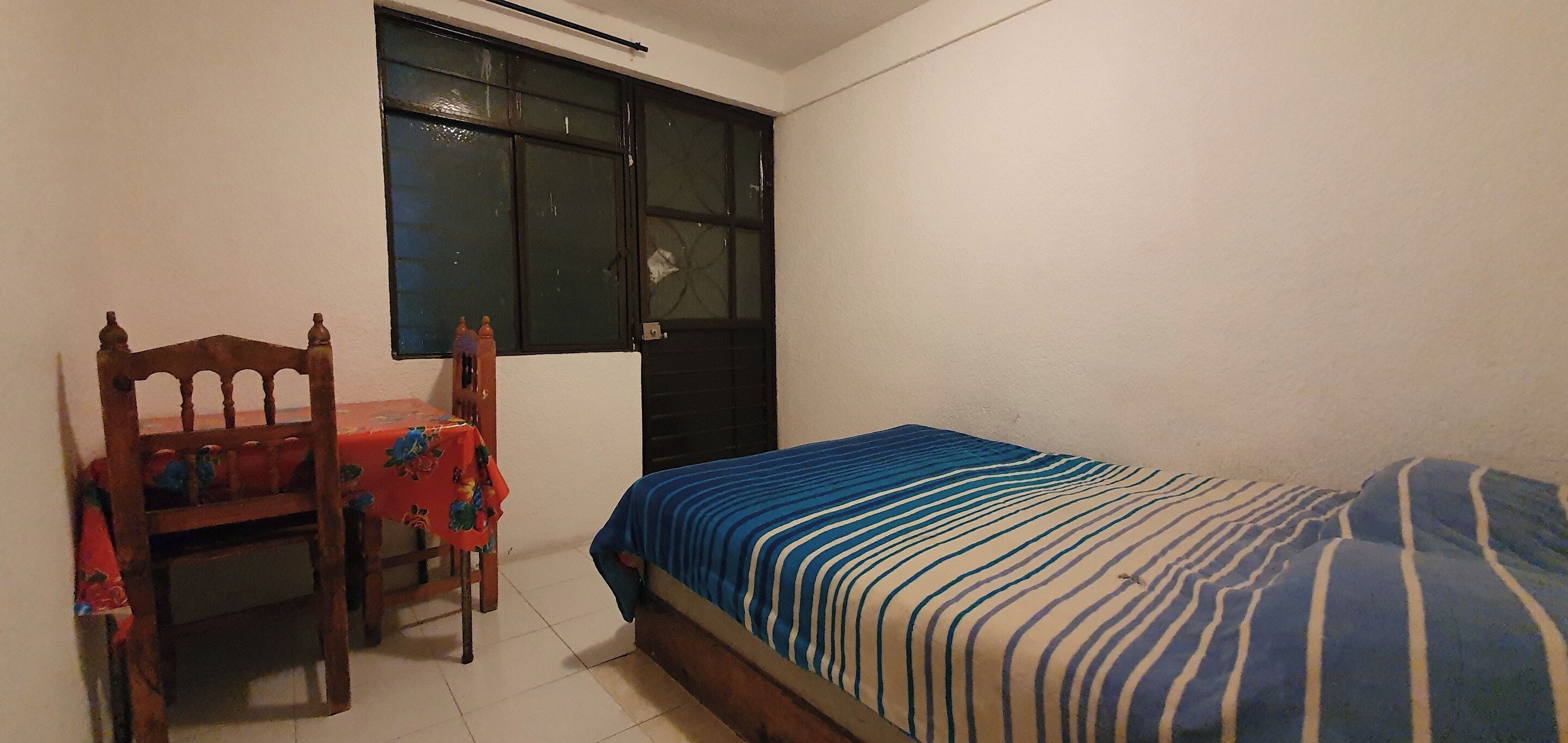 Ein Schlafzimmer mit einem Bett, einem Sessel, einem Tisch und einem Fenster.