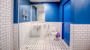 A bathroom with white and blue tiles, a white sink, a toilet, and a shower area. - Collection O To The Sea Resort Thailand (Sattahip)