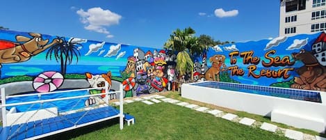 A beach-themed mural with a pool area, palm trees, and a sign reading "To The Sea Resort".