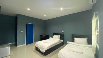 A modern hotel room with two beds, a desk, and a blue door.