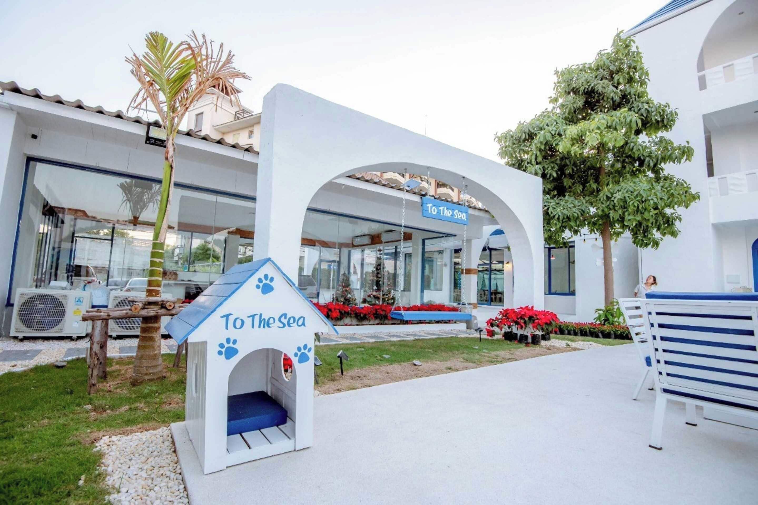 A pet-friendly hotel with a dog house labeled "To The Sea" and a sign above the entrance.