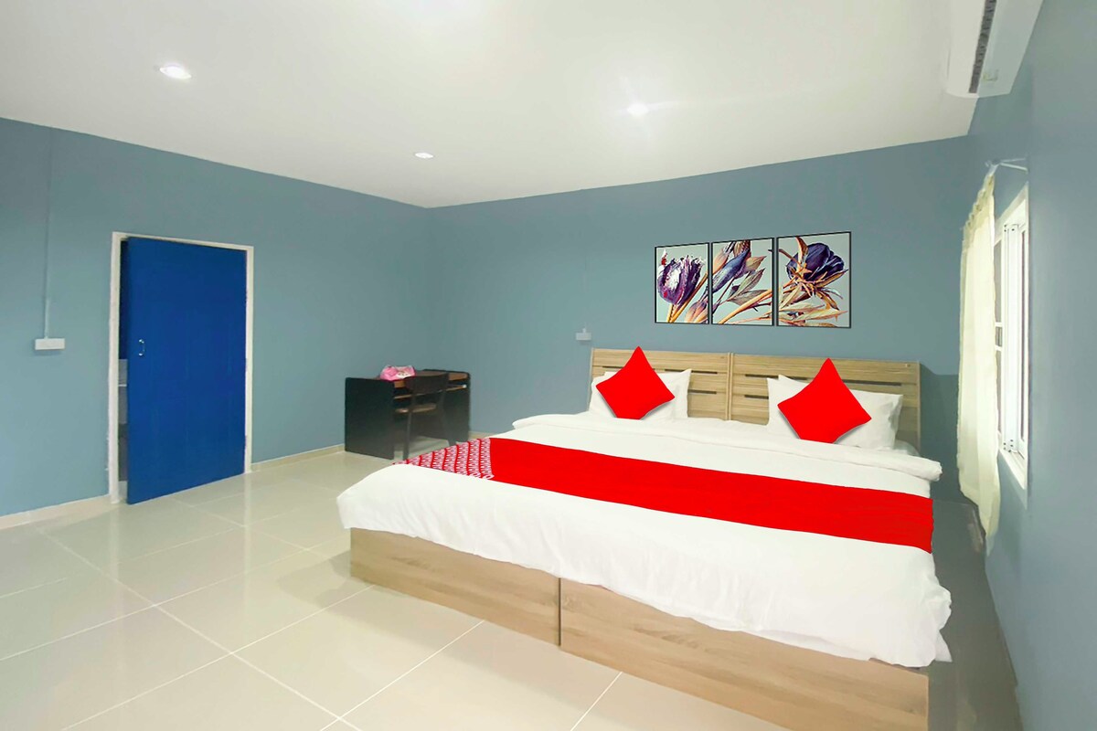 A bedroom with a bed, a desk, and a door.