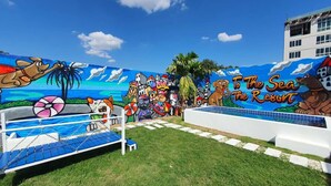 A beach-themed mural with a pool area, palm trees, and a sign reading "To The Sea Resort". - Collection O To The Sea Resort Thailand (Sattahip)