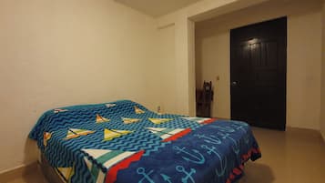 A bedroom with two beds, a door, and a wall.