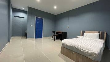A bedroom with a bed, a desk, and a chair.