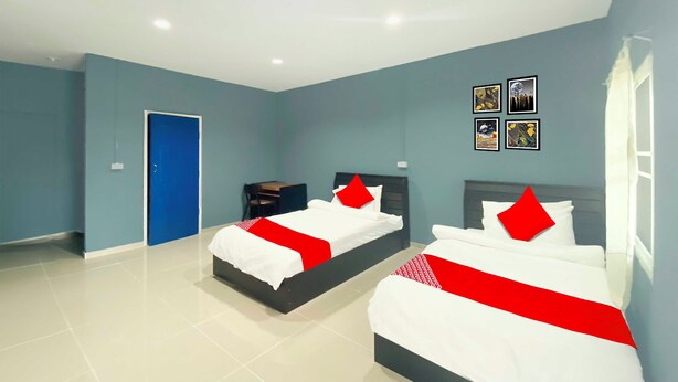 A hotel room with two beds, a blue door, and a small table. - Collection O To The Sea Resort Thailand (Sattahip)