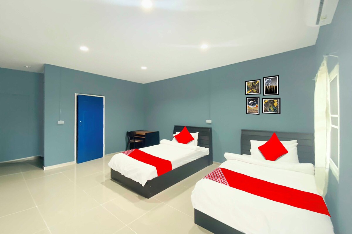 Una habitación de hotel con dos camas, una puerta azul y una pequeña mesa.