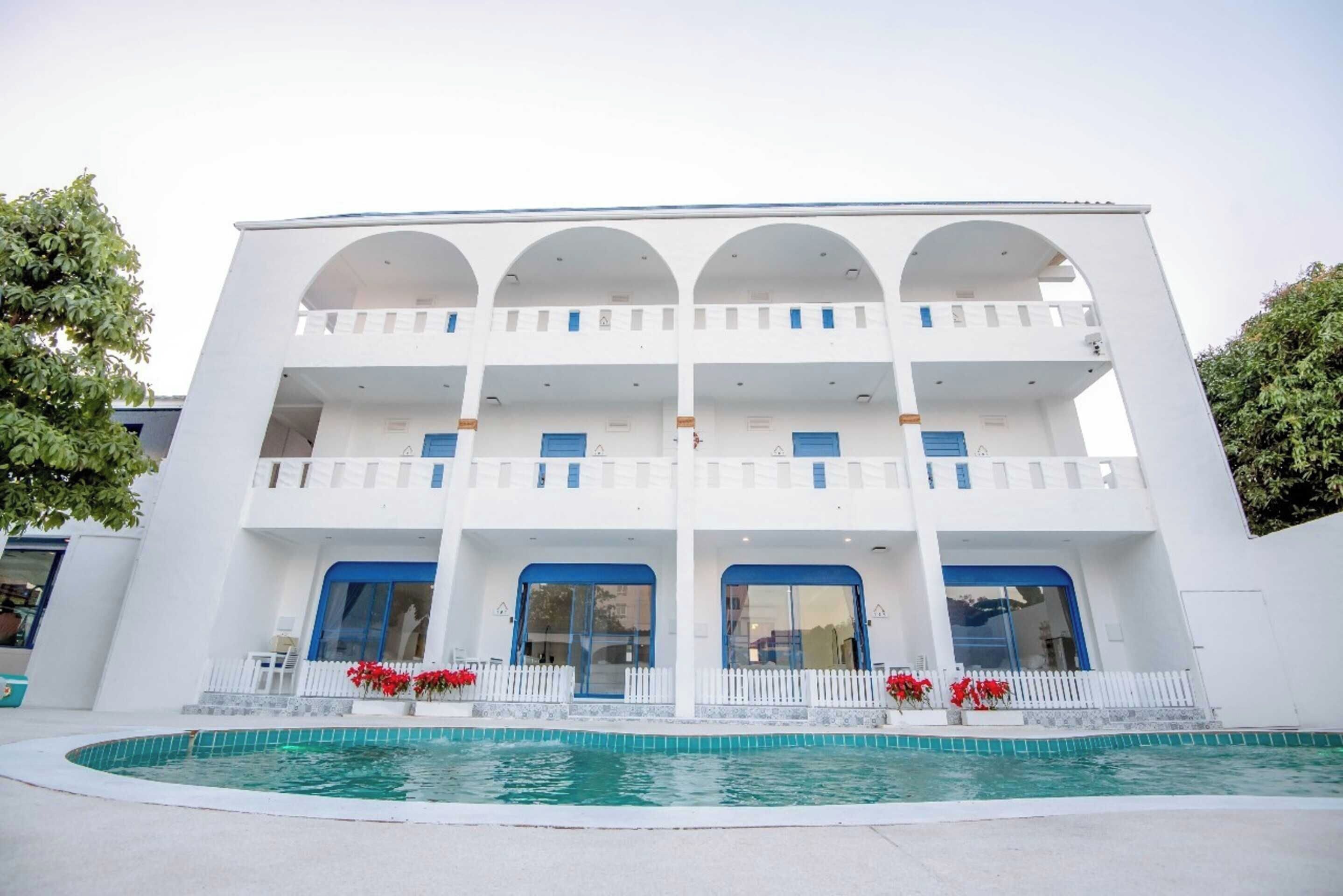 A white building with a pool in front.
