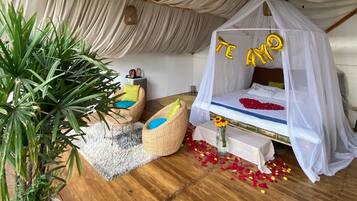 A cozy room with a canopy bed, a potted plant, and a small seating area.