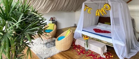 A cozy room with a canopy bed, a potted plant, and a small seating area.