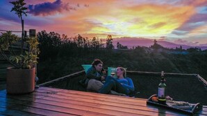 Two people sitting on a wooden deck with a sunset view. - Samay Collections (Tababela)