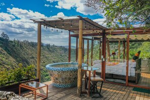 A glass-enclosed room with a bed, a small table, and a hot tub. - Samay Collections (Tababela)