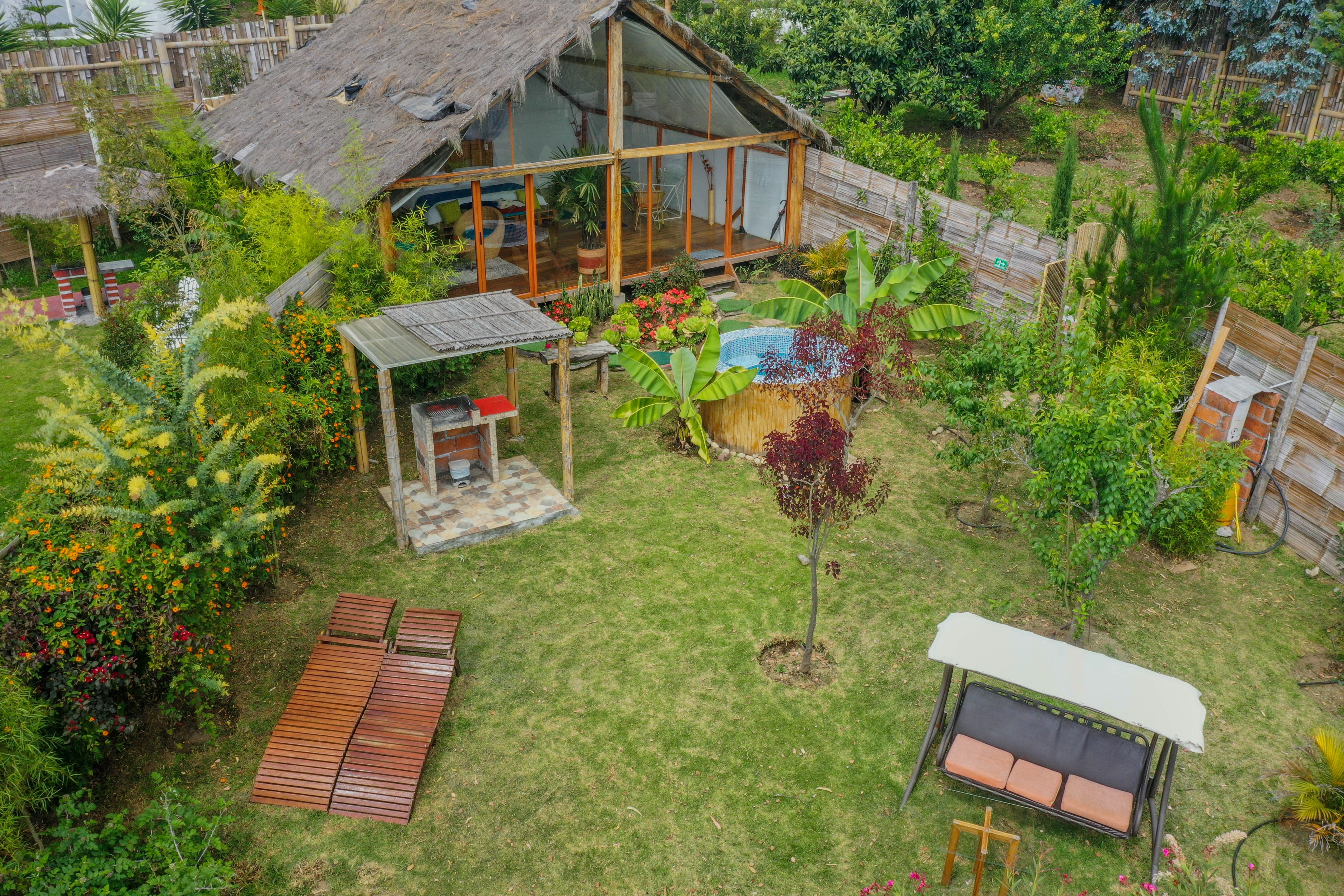 A spacious backyard with a wooden deck, a small garden, and a thatched-roof structure.