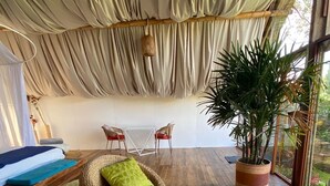 A spacious room with a large potted plant, wicker furniture, and a view through large windows. - Samay Collections (Tababela)