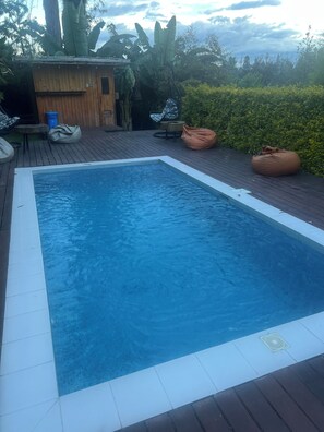 A rectangular swimming pool with a wooden deck surrounding it. - Samay Collections (Tababela)