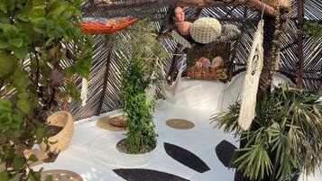 A hammock suspended from a bamboo structure, surrounded by lush greenery and a decorative painting.