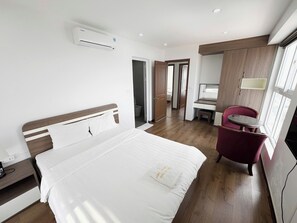 A hotel room with a bed, a desk, a chair, and an air conditioning unit. - New Life Tower Bai Chay (Bai Chay)