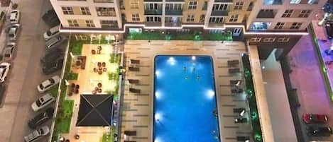 Vue aérienne d’un immeuble résidentiel doté d’une piscine, d’un espace de détente extérieur et d’un parking.
