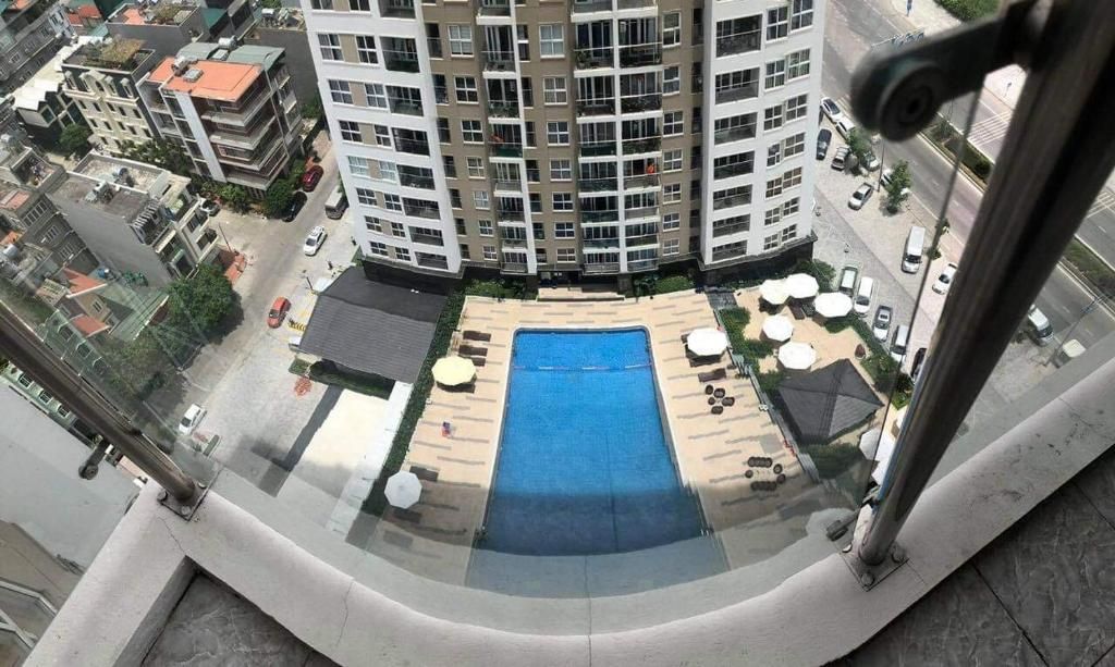 A high-rise building with a rooftop pool area, including sun loungers and umbrellas.