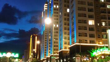 Una calle urbana iluminada de noche, con edificios altos, farolas y vehículos.