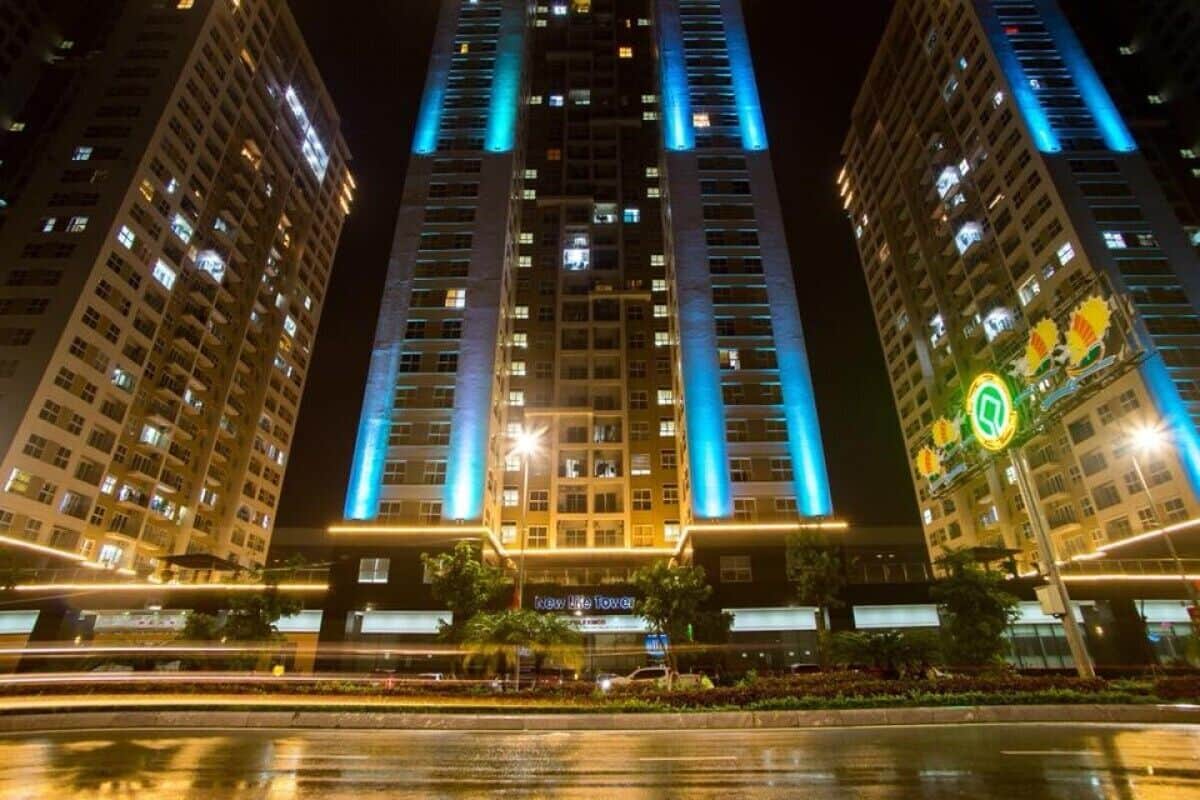 A high-rise hotel with illuminated vertical lines on the facade, a central entrance, and a sign reading "New Life Tower".