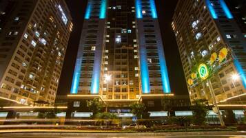 Un hotel de gran altura con líneas verticales iluminadas en la fachada, una entrada central y un letrero que dice "New Life Tower".