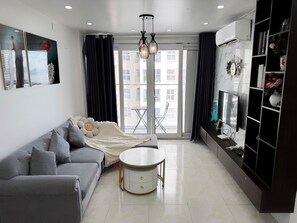 A modern living room with a grey sofa, a round coffee table, and a TV on a dark wooden cabinet. - New Life Tower Bai Chay (Bai Chay)