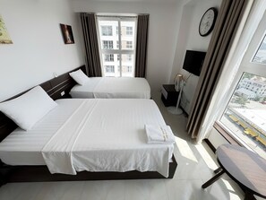 A hotel room with two beds, a bedside table, a TV, and a window with curtains. - New Life Tower Bai Chay (Bai Chay)