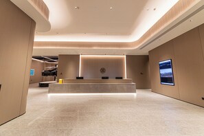 A modern lobby with a reception desk, a large wall-mounted screen, and a clean, minimalist design. - Xianze Hotel (Guangzhou)
