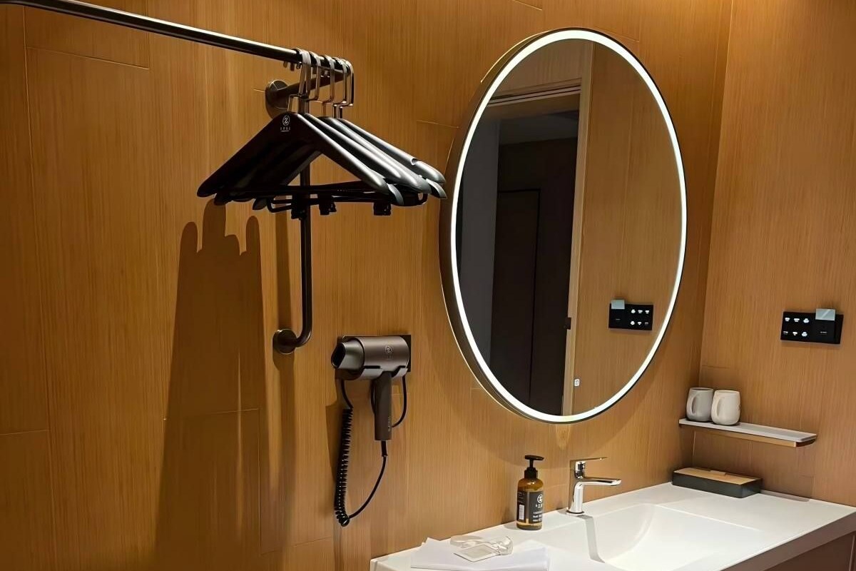 A modern bathroom with a white sink, a mirror, a towel rack, and a hairdryer.