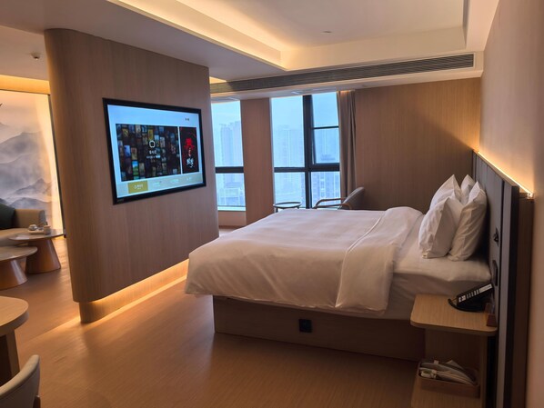 A modern hotel room with a large bed, a desk, a TV mounted on the wall, and a large window with a city view. - Xianze Hotel (Guangzhou)