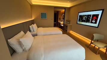 A hotel room with two beds, a TV, and a desk with a chair.