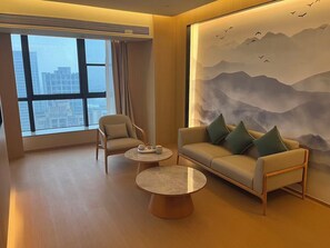A modern hotel room with a large window, a sofa, a chair, and a small table. - Xianze Hotel (Guangzhou)