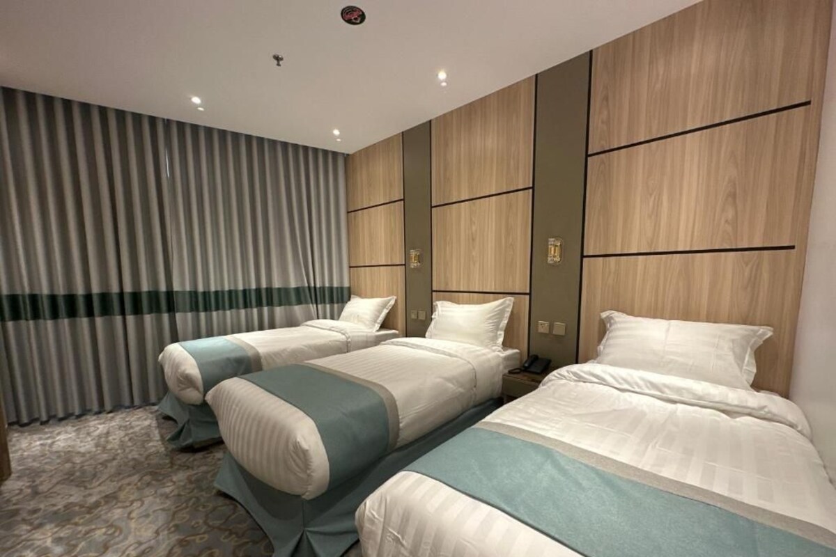 Een hotelkamer met twee bedden, een groot raam met gordijnen en een houten accentmuur.