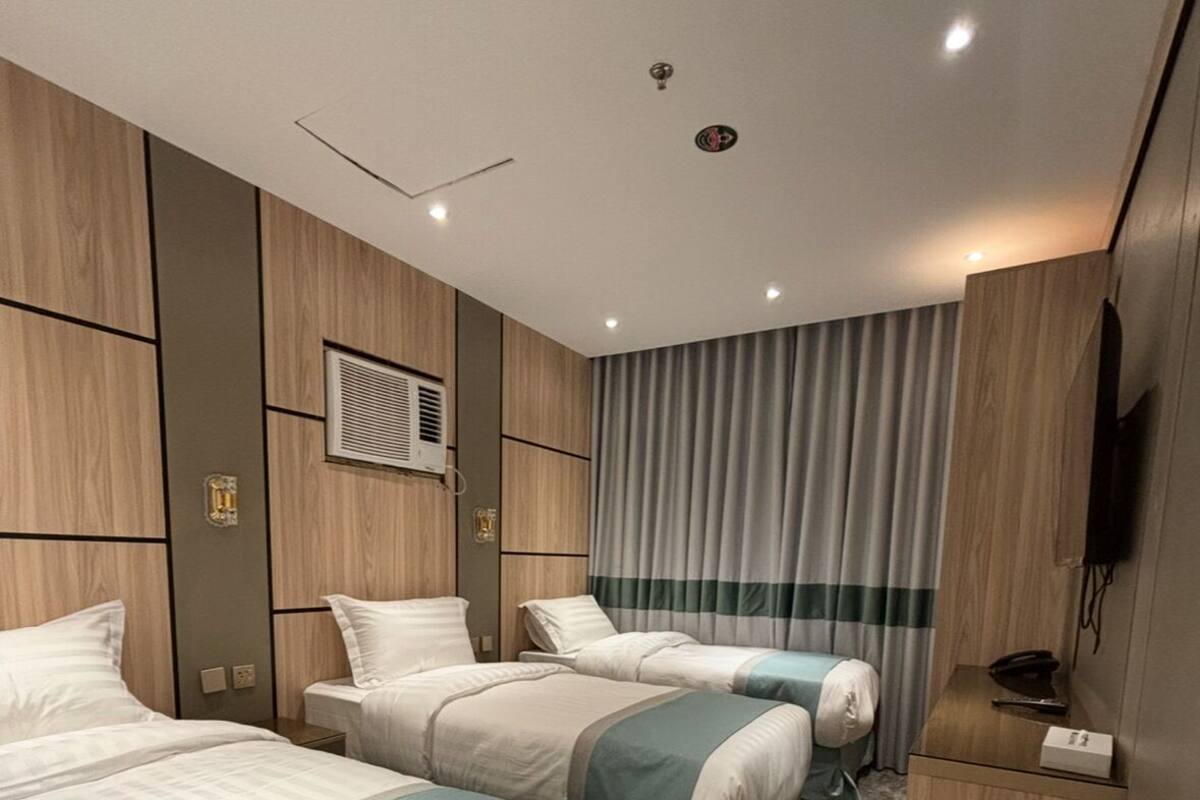Une chambre d’hôtel avec deux lits, une télévision, une poubelle et une moquette à motifs.